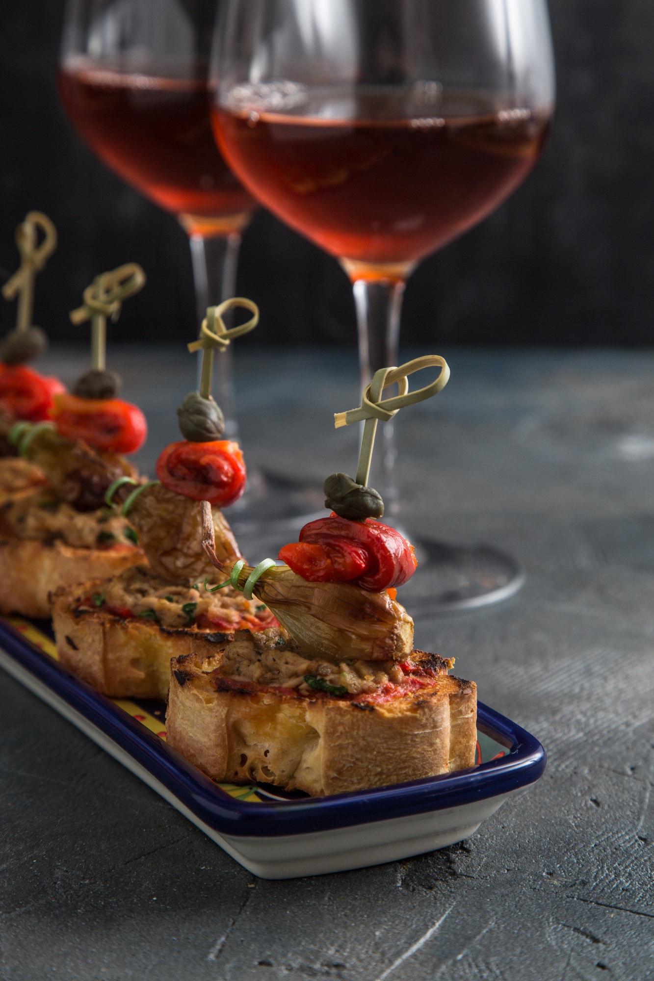 spanish tapa pinxtos with tuna, peper, onion and oregano. Wine on background