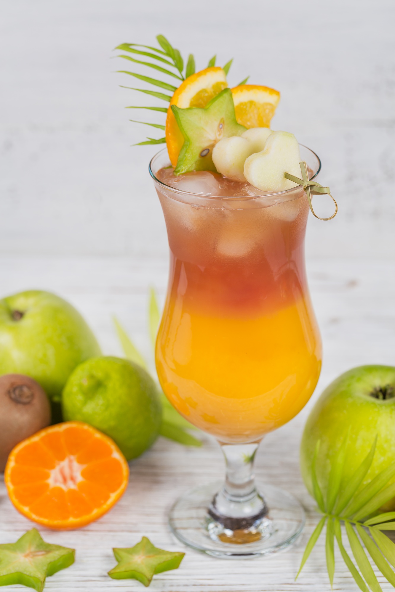 Summer cocktail with various tropical fruits around.